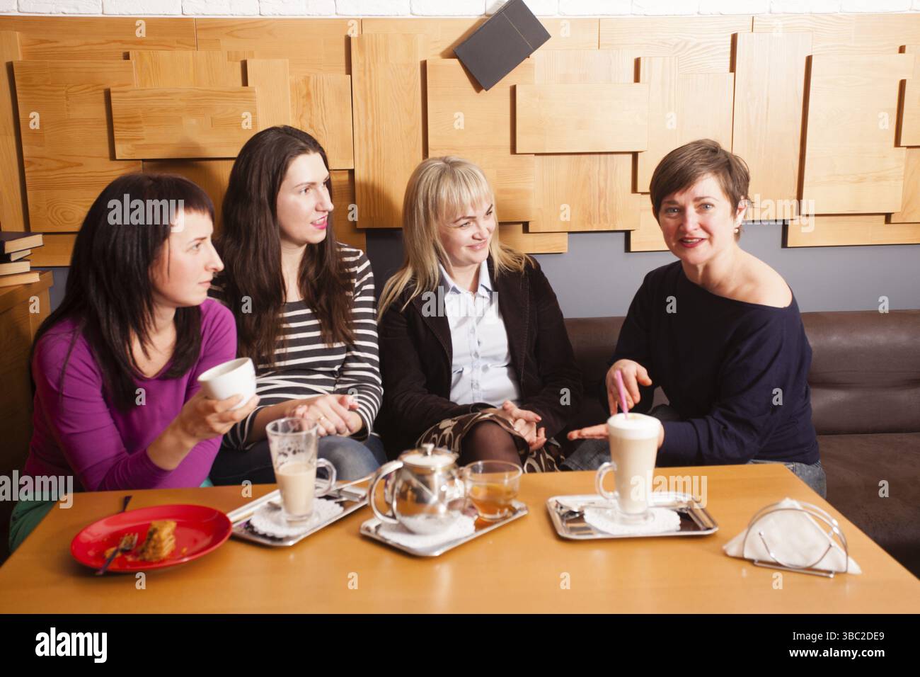 Amiche a discutere le ultime notizie durante la riunione informale nella caffetteria Foto Stock