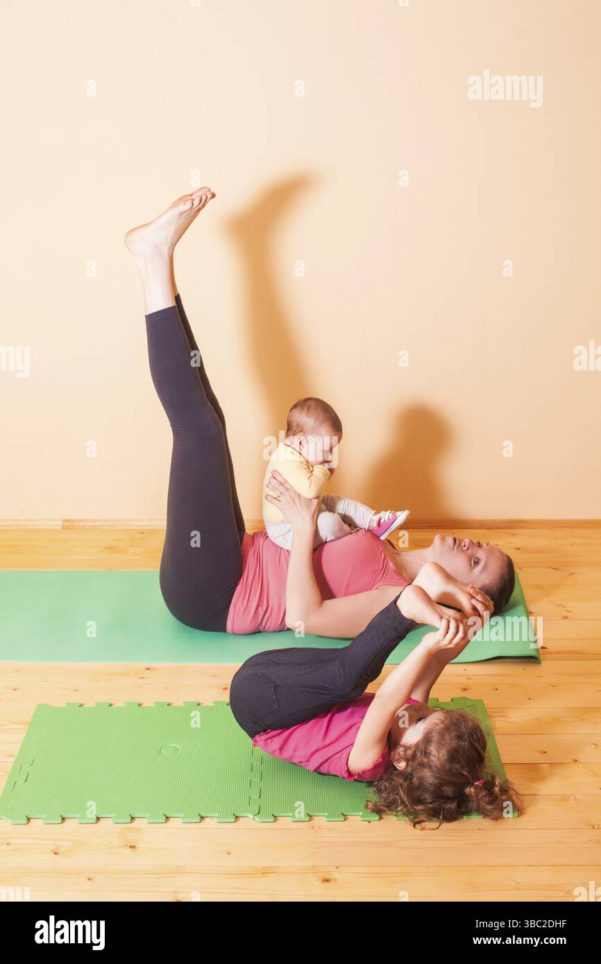 La mamma con due bambini facendo esercizi yoga in home Foto Stock