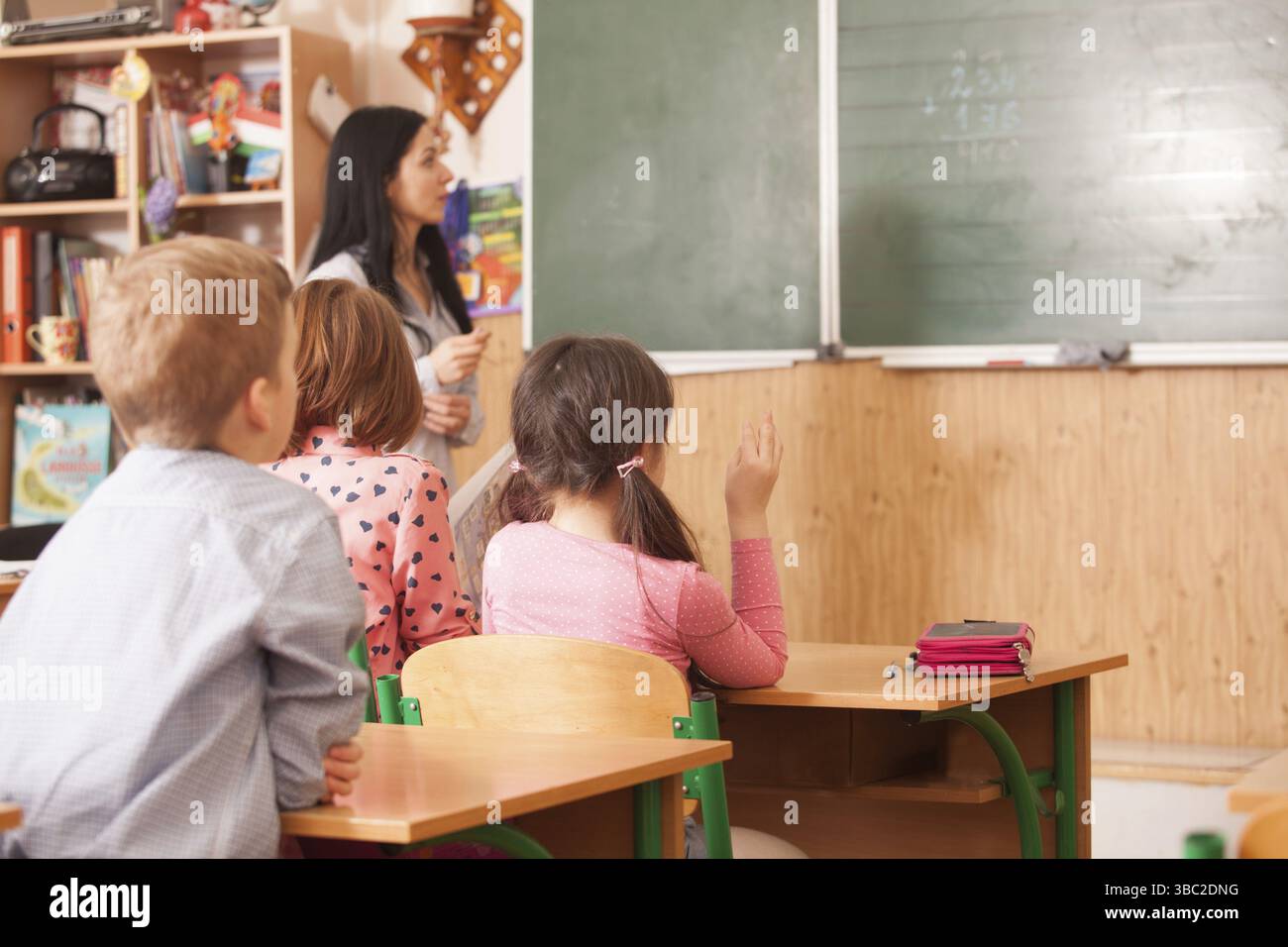 Insegnante di donna aiutando la pupilla per risolvere esempio matematico a lavagna Foto Stock