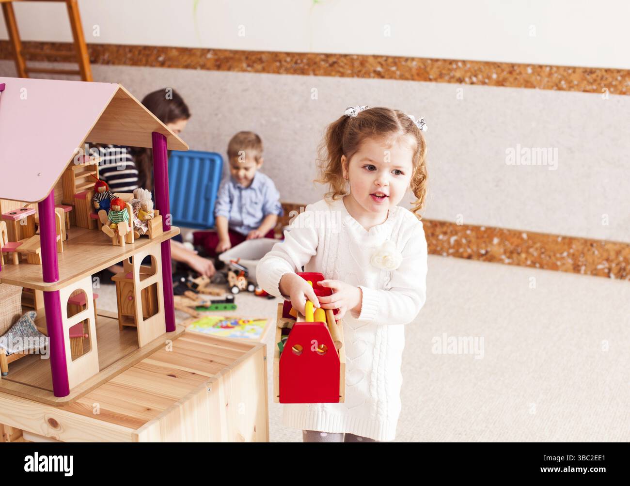 Pretty girl ripara il tetto di dollhouse nella scuola materna Foto Stock