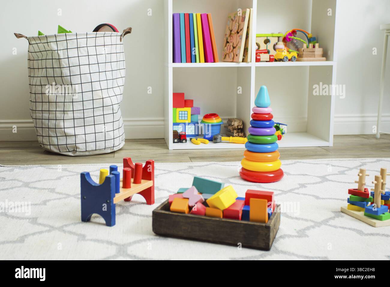 Varietà di giocattoli educativi in legno e plastica lasciati su un tappeto bianco dopo i giochi per bambini. Asilo nido o asilo con giocattoli Foto Stock