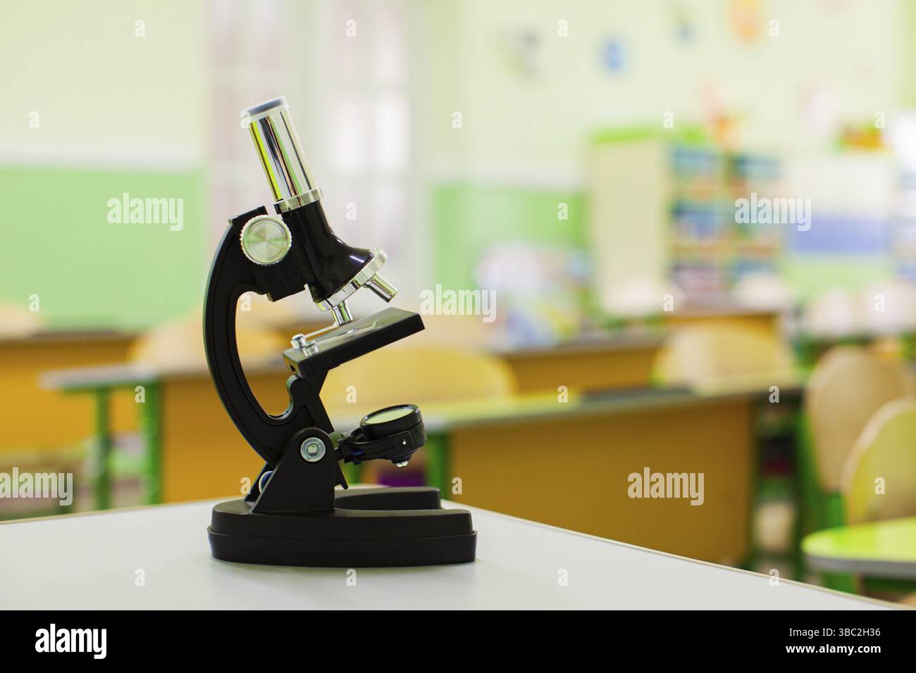 Attrezzature scolastiche per lezioni di biologia. Microscopio nero sulla scrivania della scuola. Accessori visivi per lezioni naturali per giovani studenti Foto Stock