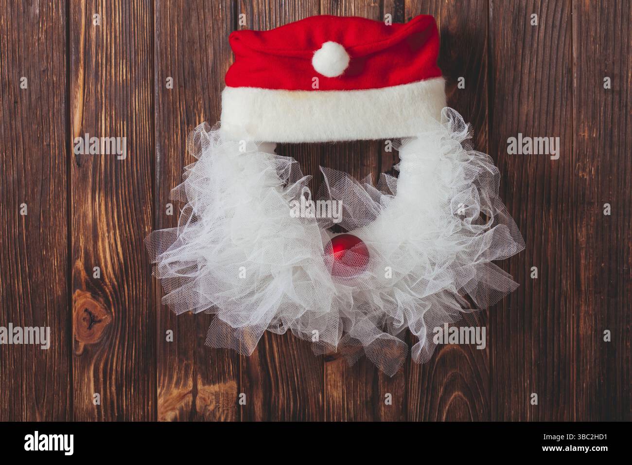 Corona di Natale come Santa testa da pizzo e baule rosso sulla porta di legno Foto Stock