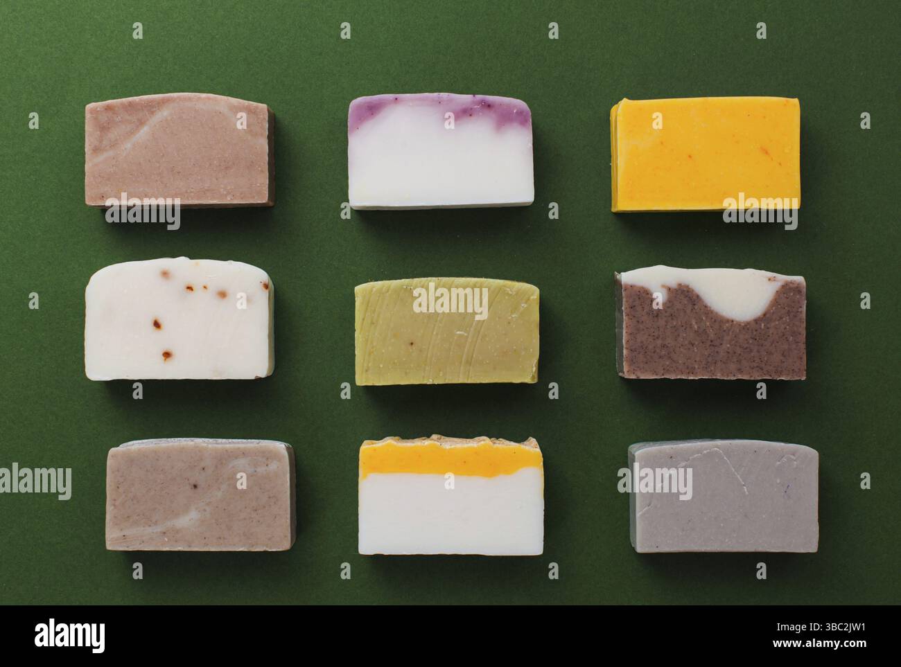 Composizione a posa piatta con saponette fatte a mano su sfondo verde scuro, vista dall'alto. Prodotti biologici sani di bellezza Foto Stock