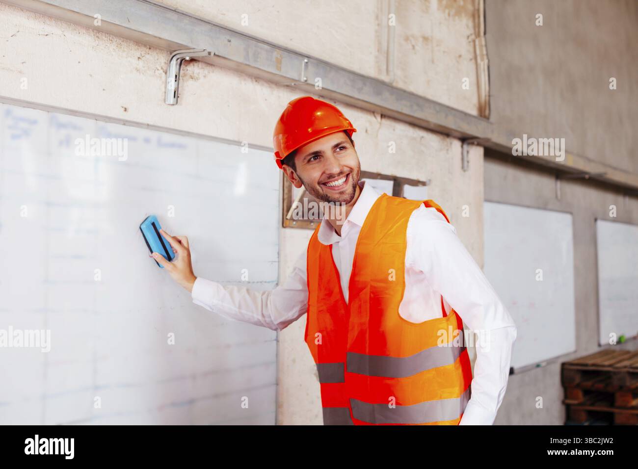 Il tecnico esperto fa le pratiche per i principianti alla fabbrica. Gli ingegneri si stanno levando in piedi accanto da flip chat Foto Stock
