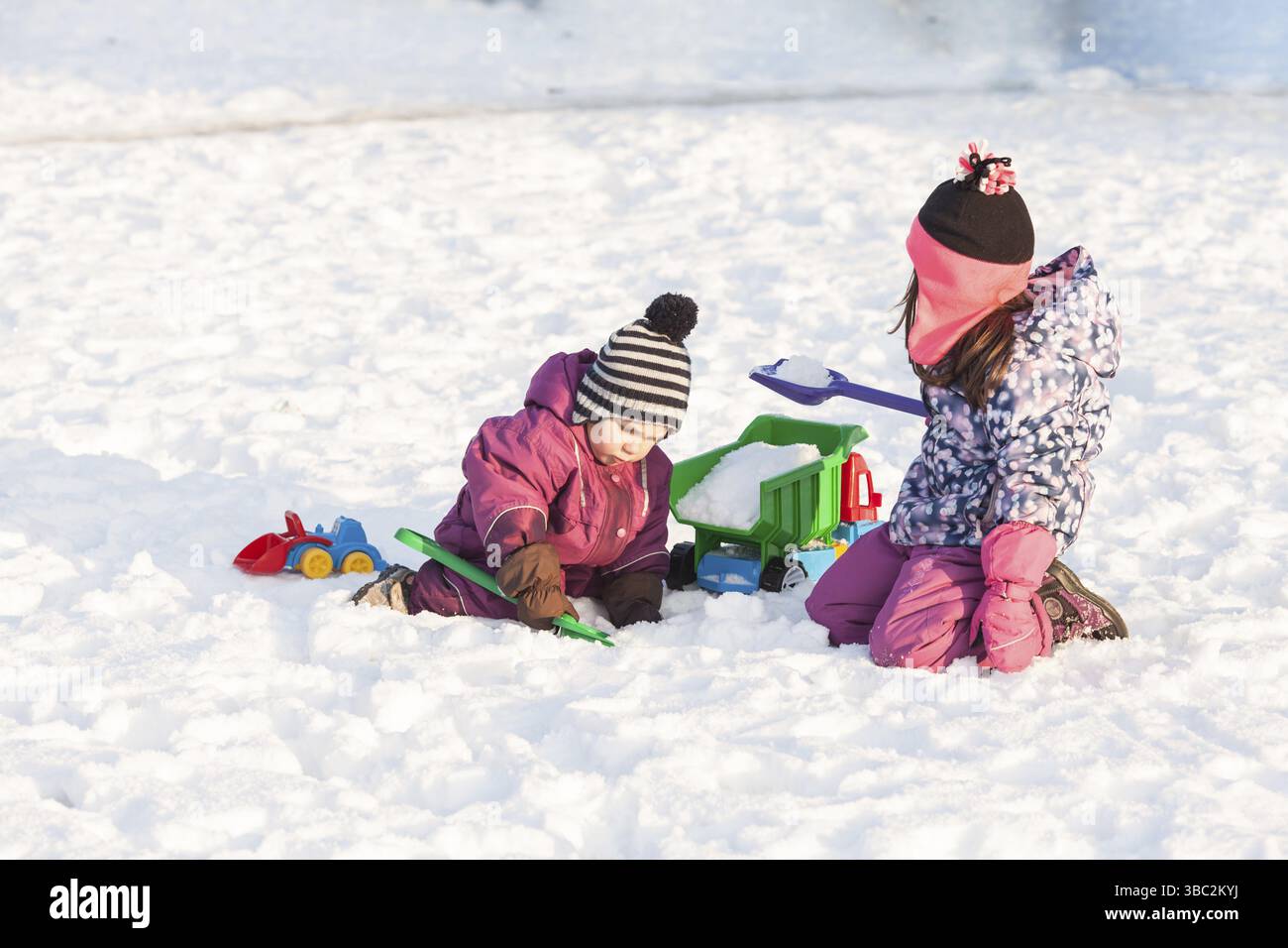 I bambini giocano con le automobili e pale. Città di neve il concetto di pulizia Foto Stock