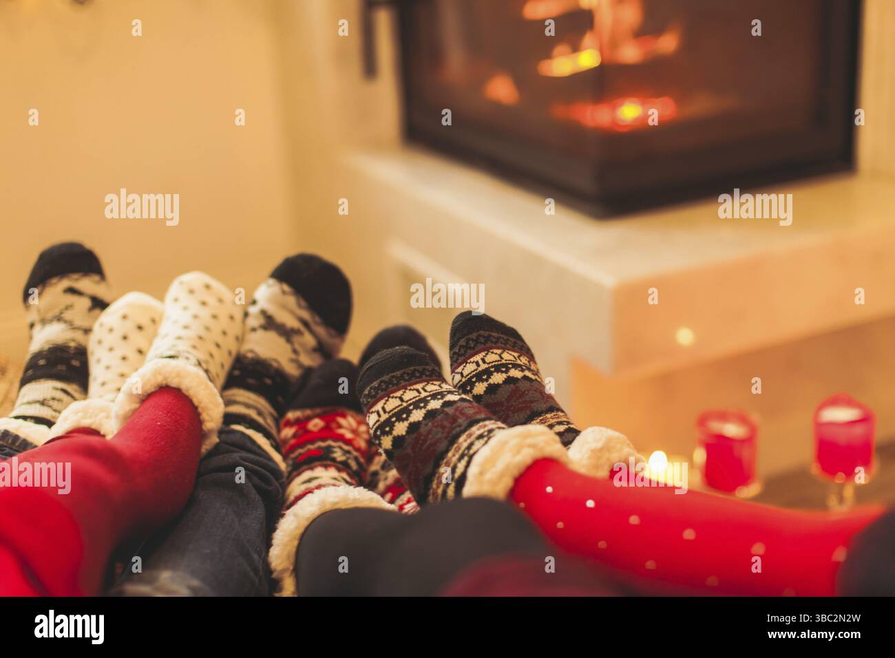 La grande famiglia è in fase di preriscaldamento vicino al caminetto in inverno freddo giorno. Interiour moderno, concentrarsi sulle calze Foto Stock