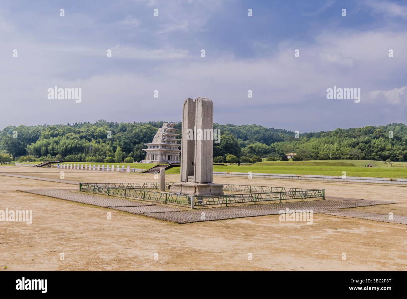 Iksan, Corea del Sud. 8 luglio 2020: Paesaggio del sito archeologico con l'antico supporto di un'asta in pietra e Pagoda in pietra Mireuksaji sullo sfondo Foto Stock