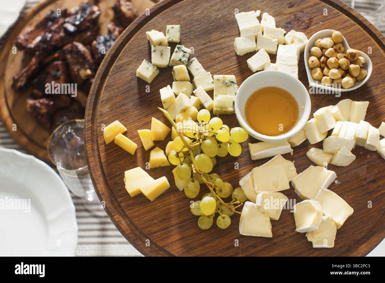 Il piatto di formaggi con nocciole, miele, uva sulla tavola di legno sul tavolo serviti Foto Stock