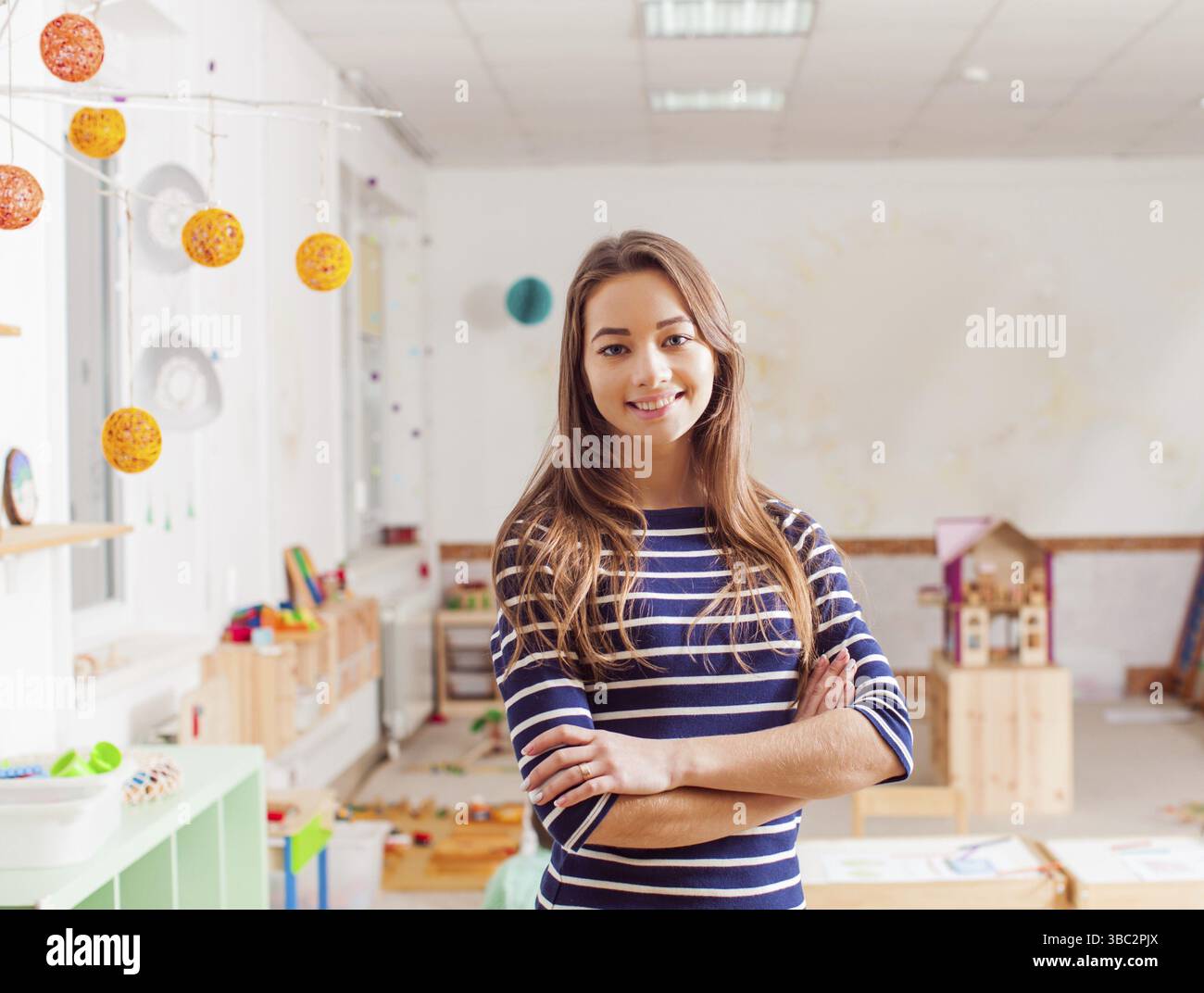 Sorridente in età prescolare giovane insegnante in una scuola materna Waldorf Foto Stock