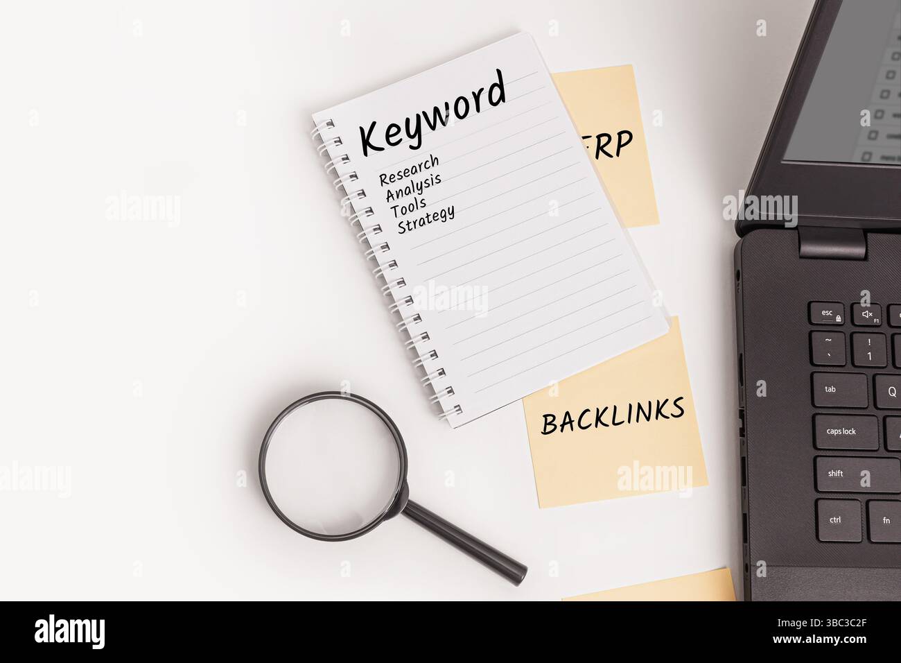 Un notebook con la parola parola parola chiave, ricerca, analisi, strumenti e strategia, con appunti adesivi etichettati Backlinks, una lente di ingrandimento e un laptop. Foto Stock