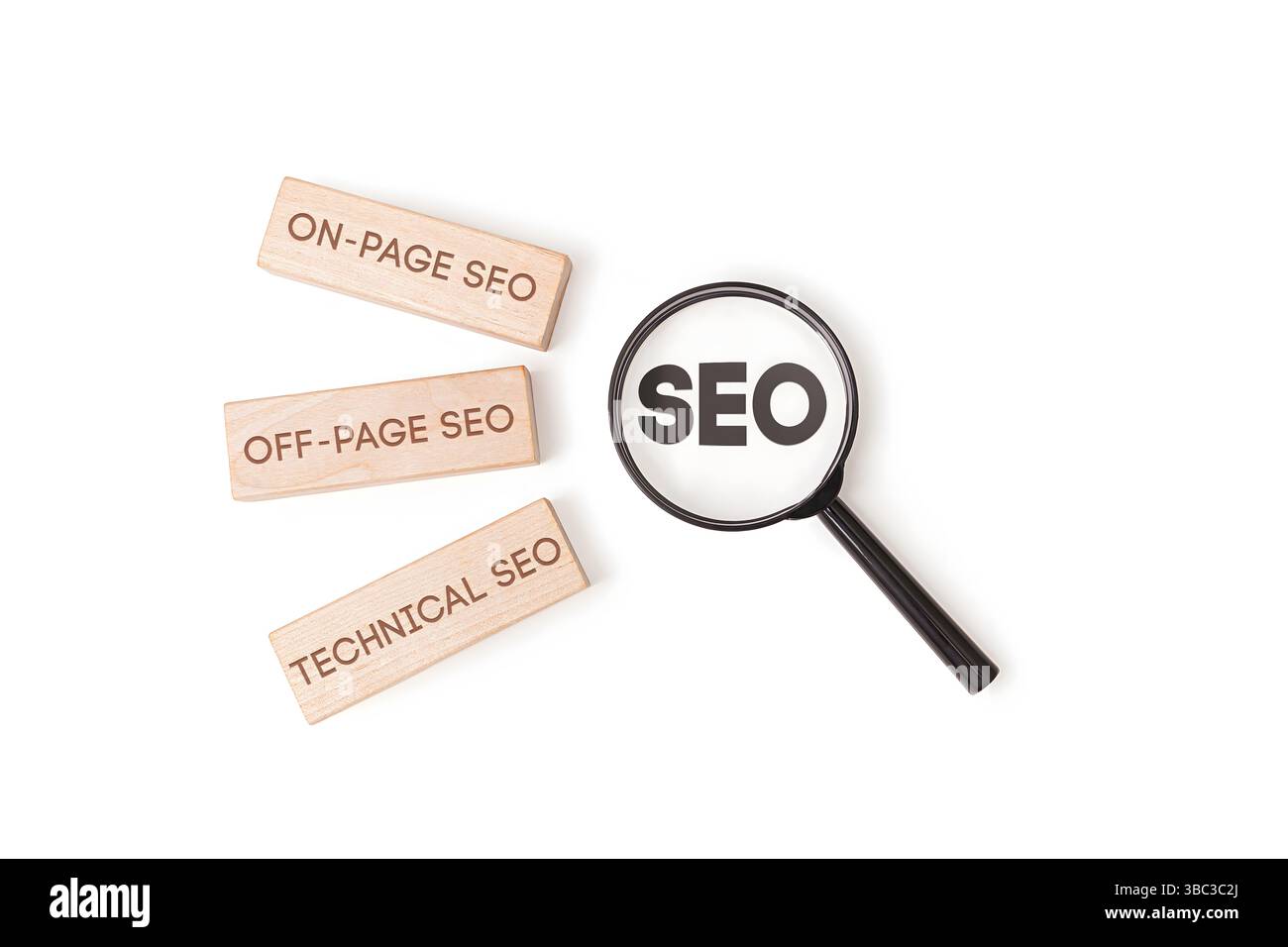 "Tre blocchi di legno etichettati "SEO on-page", "SEO off-page", "SEO tecnico" accanto a una lente di ingrandimento che concentra la parola "SEO" su sfondo bianco. Foto Stock
