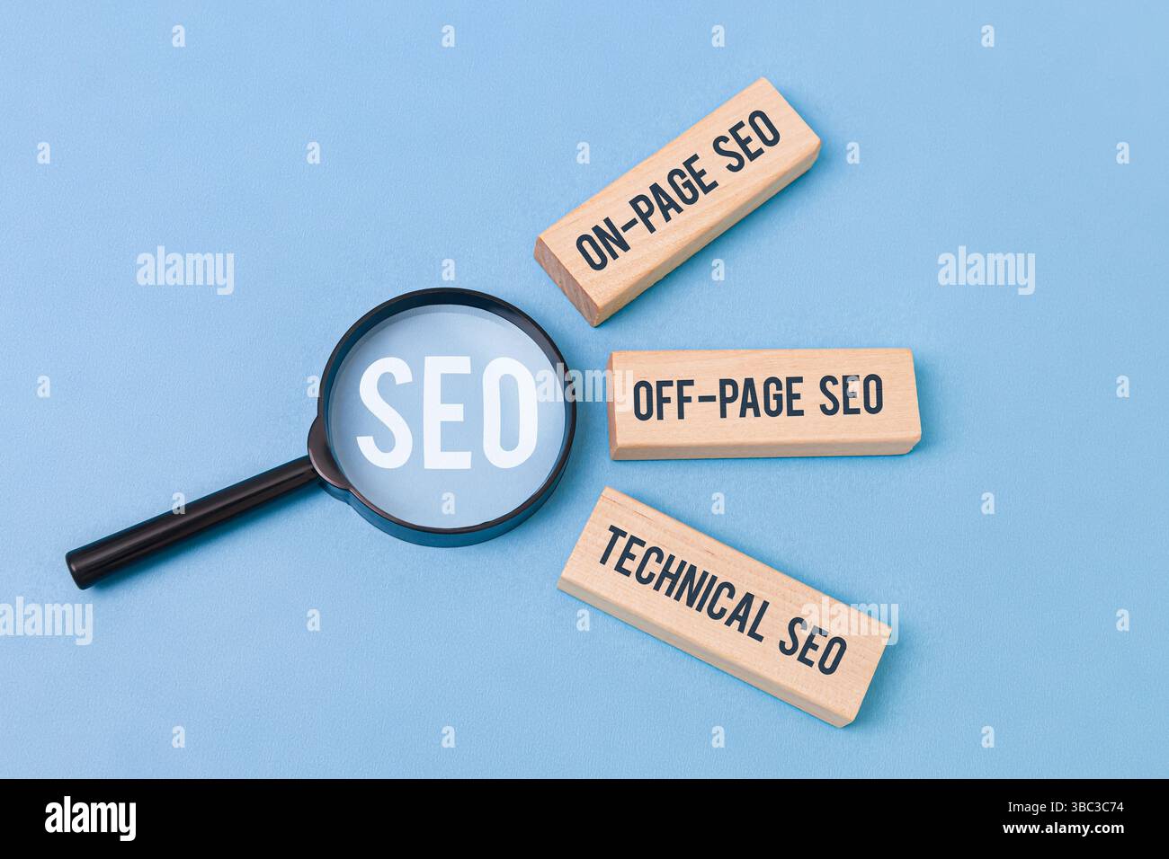 "Tre blocchi di legno etichettati "SEO on-page", "SEO off-page", "SEO tecnico" accanto a una lente di ingrandimento che concentra la parola "SEO" su sfondo blu. Foto Stock