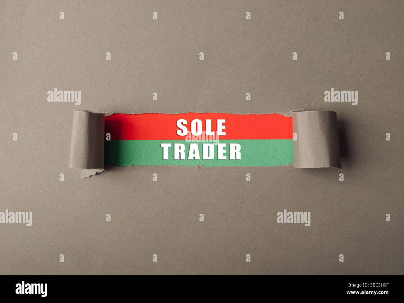 Strappato un pezzo di carta con scritto sopra la parola Sole Trader. La carta è strappata a metà e presenta una striscia rossa e verde Foto Stock