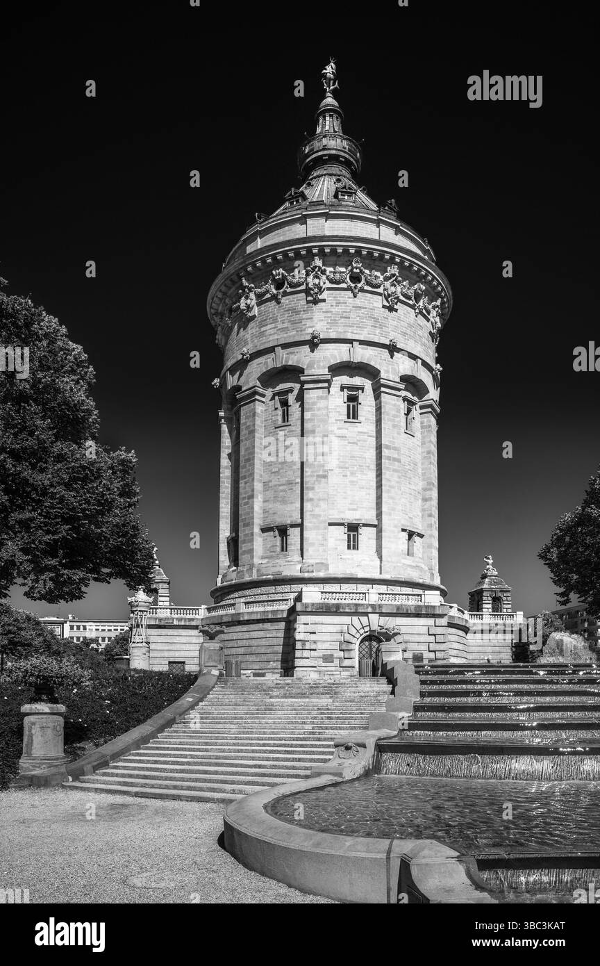 La torre d'acqua di Mannheim, Germania, presenta intricati lavori in pietra tra vegetazione lussureggiante e sentieri sereni, che incarnano l'eleganza storica. Foto Stock