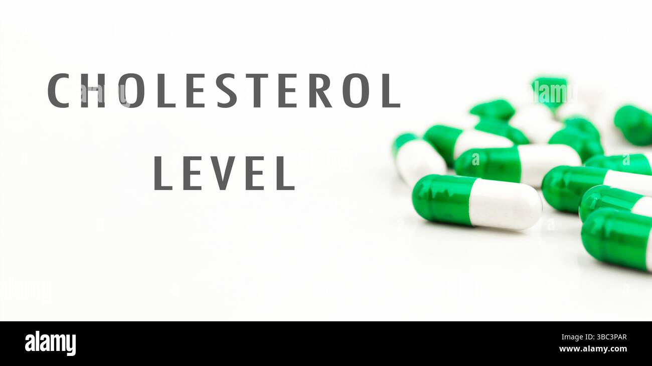 Pillola verde e bianca su sfondo bianco. La pillola è etichettata come livello di colesterolo. Ci sono molte pillole sullo sfondo Foto Stock
