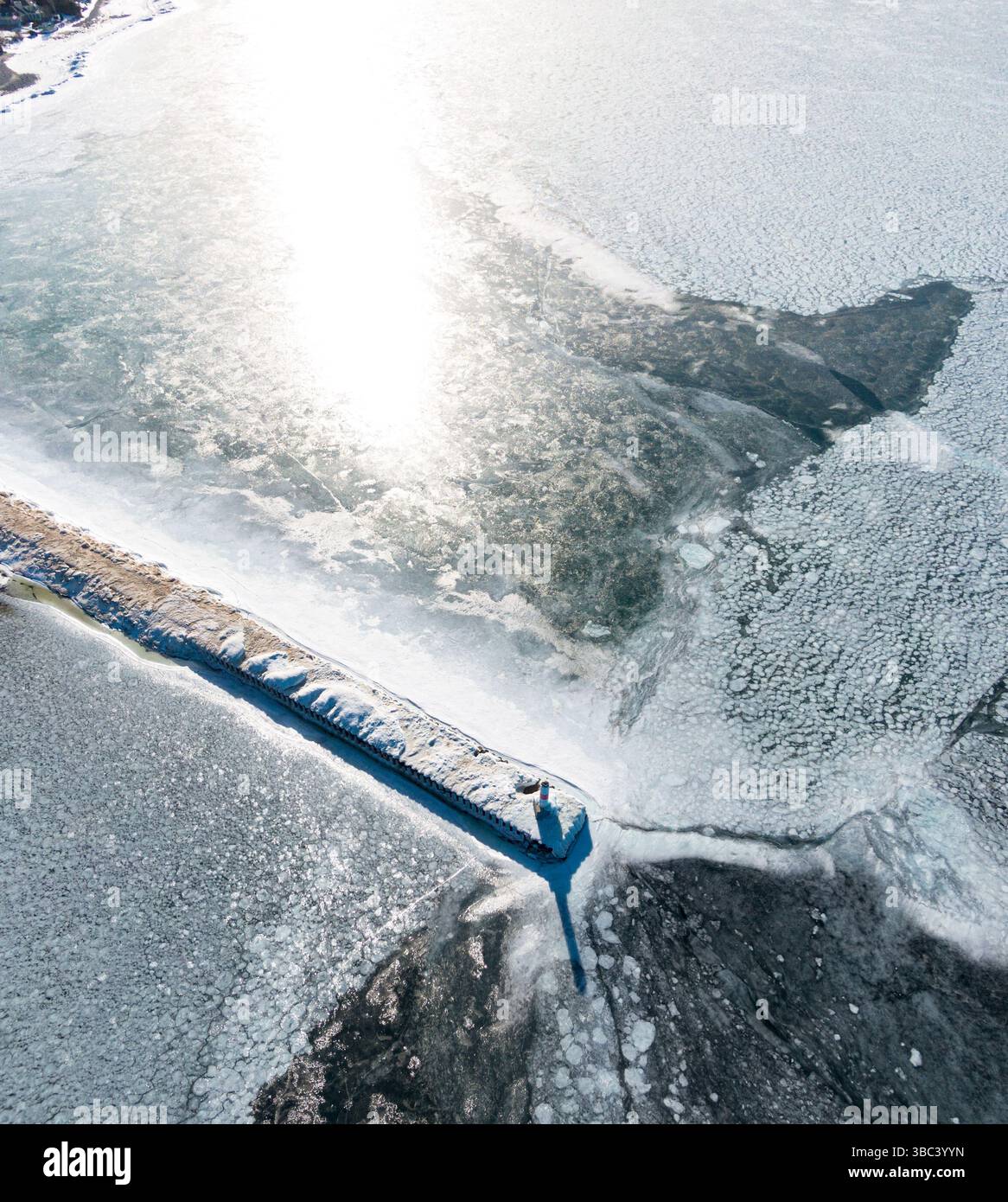 Vista aerea di un faro circondato da acque ghiacciate in inverno Foto Stock
