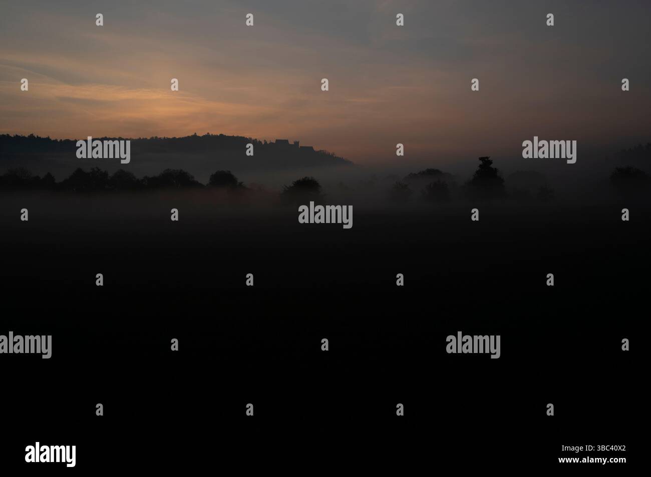 Nebbia al sorgere del sole con il castello di Weitenburg sullo sfondo nel paesaggio della valle del Neckar vicino a Rottenburg am Neckar in Germania. Foto Stock