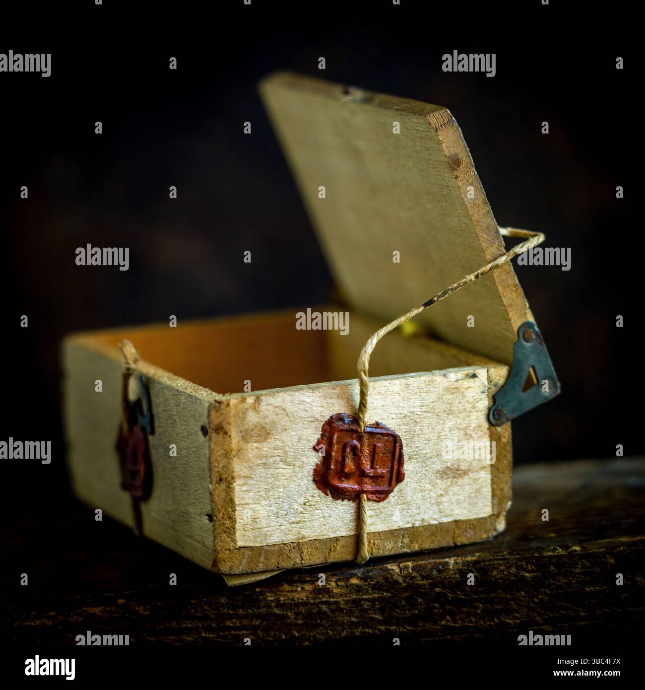 Una scatola di legno è fissata con spago, con un sigillo di cera rosso intenso che significa autenticità e qualità. Foto Stock
