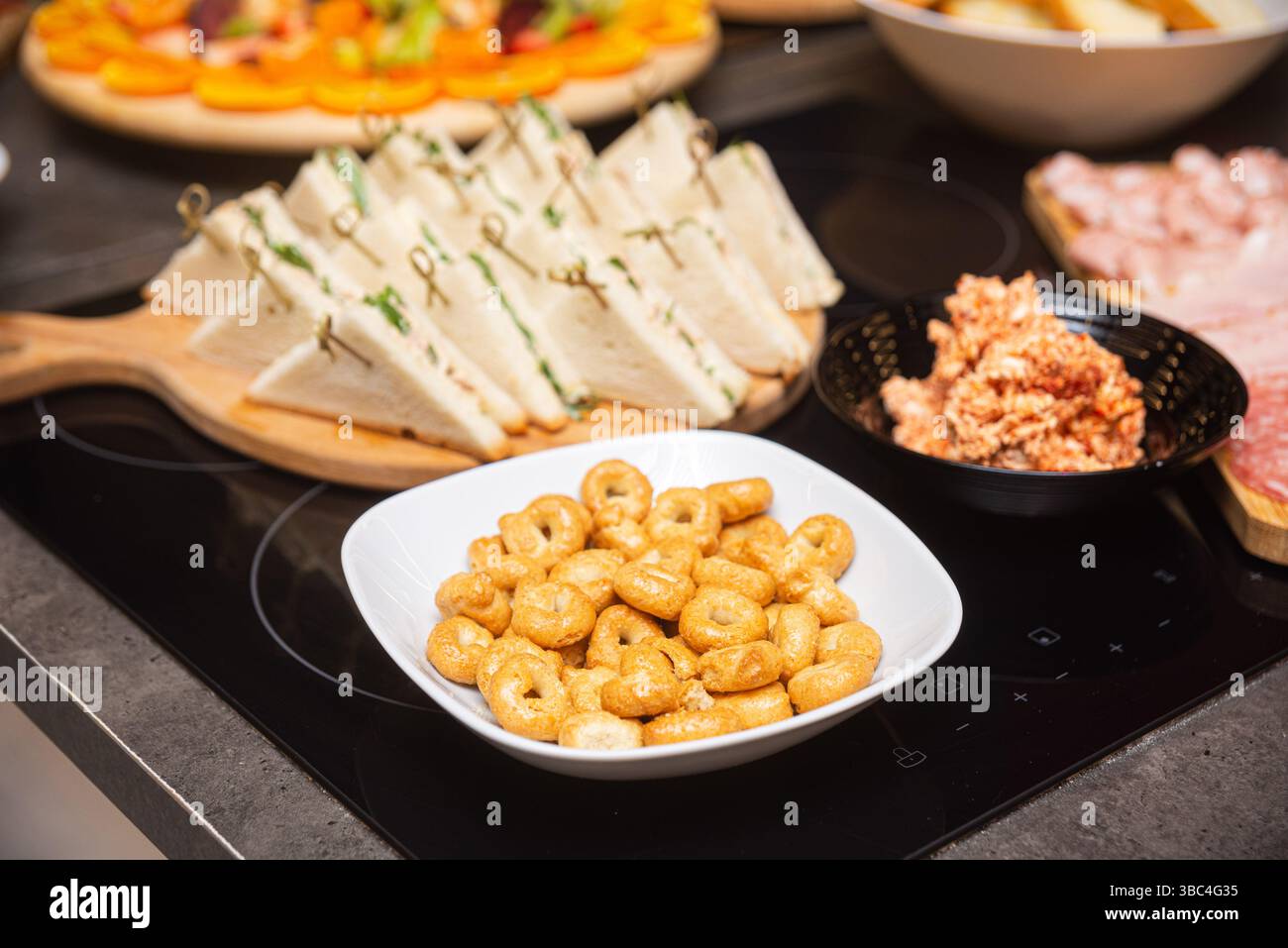 Stuzzichini italiani assortiti, tra cui taralli, cremosi panini e affettati serviti su un tavolo a buffet per aperitivo o festa. Foto Stock