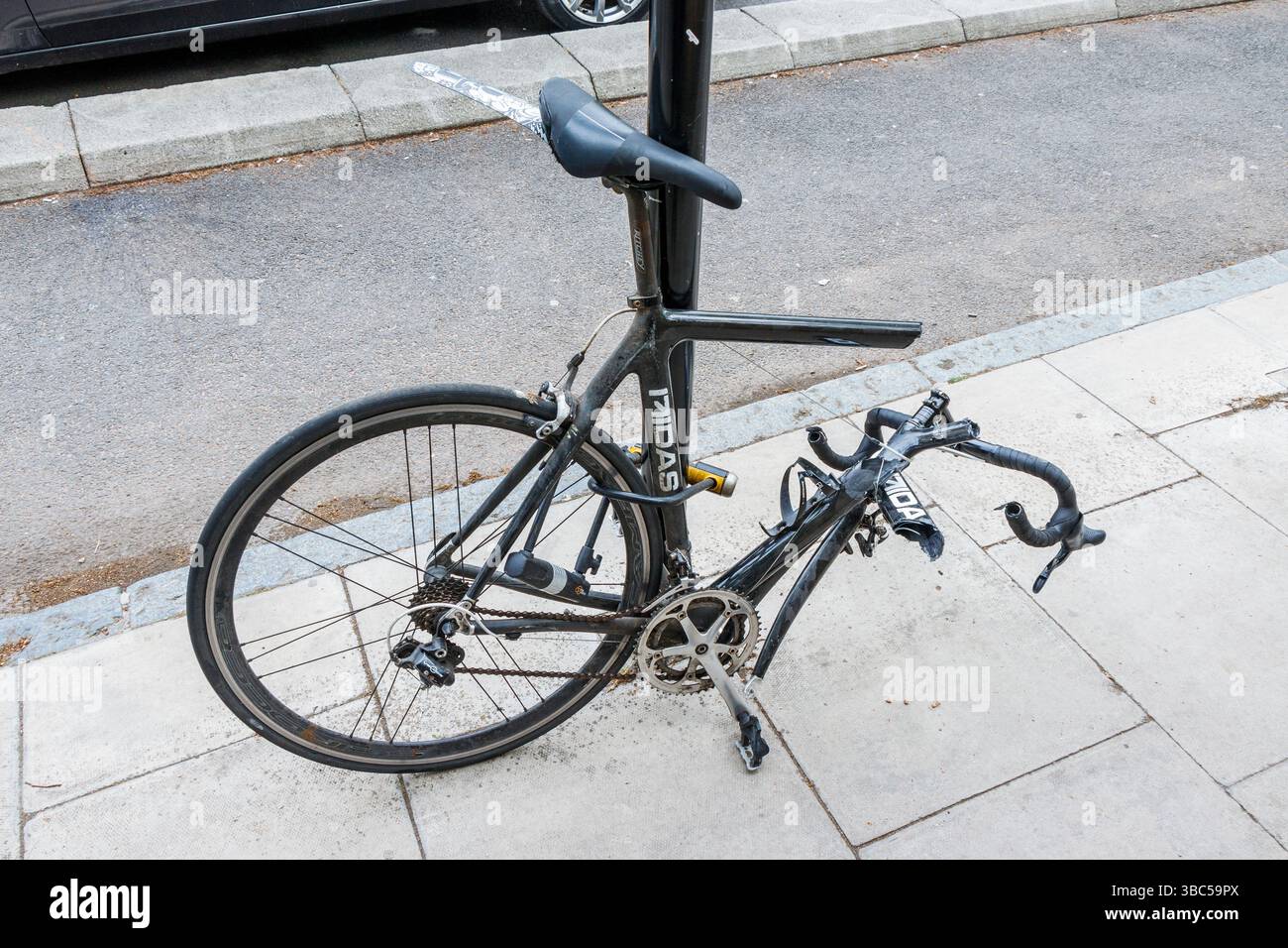 Una bicicletta nera vandalizzata incatenata a un palo, il telaio è stato segato, Londra, Regno Unito Foto Stock