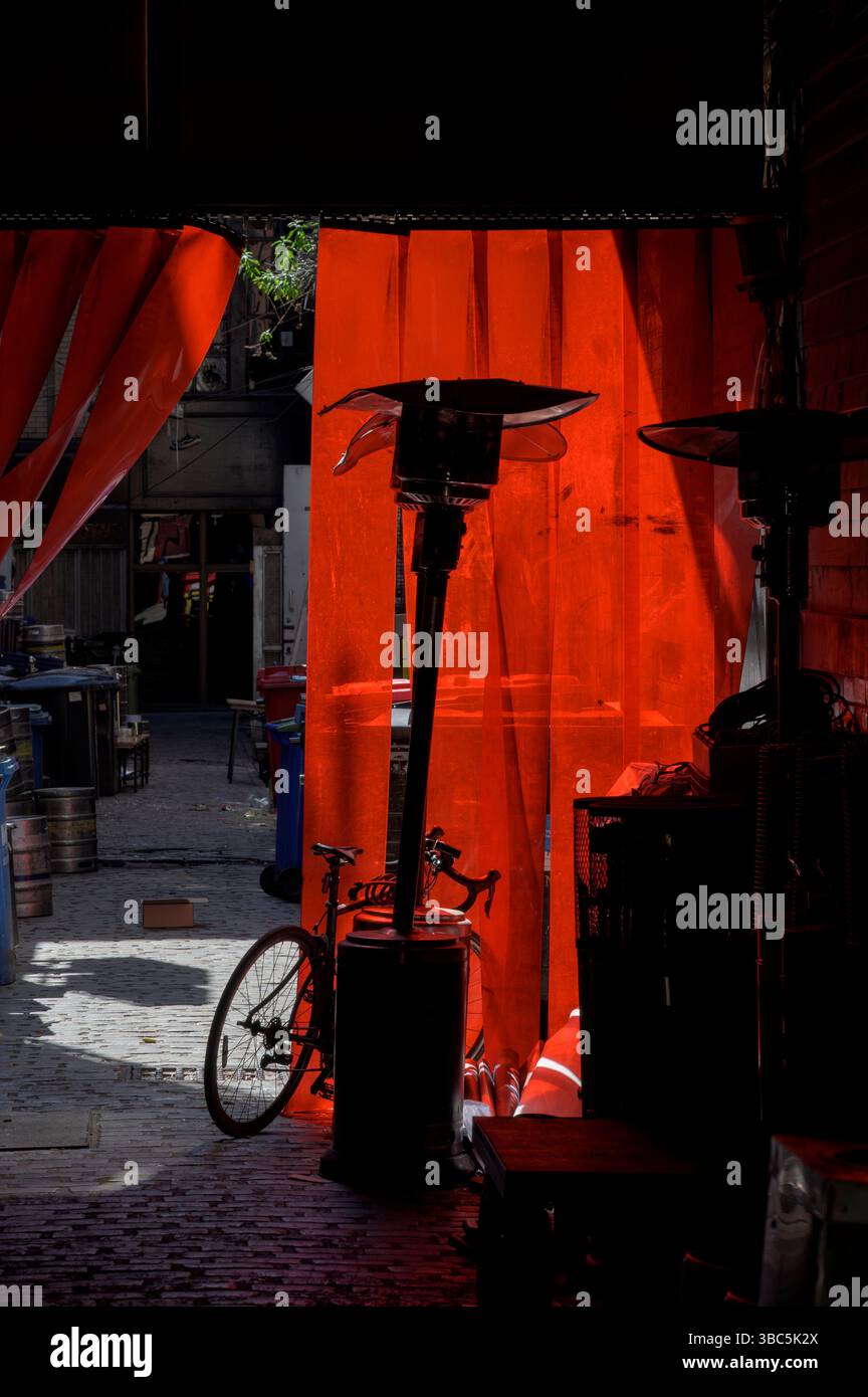 Luce solare che cade su tende di plastica rosse in una corsia di servizio aziendale, Regno Unito Foto Stock