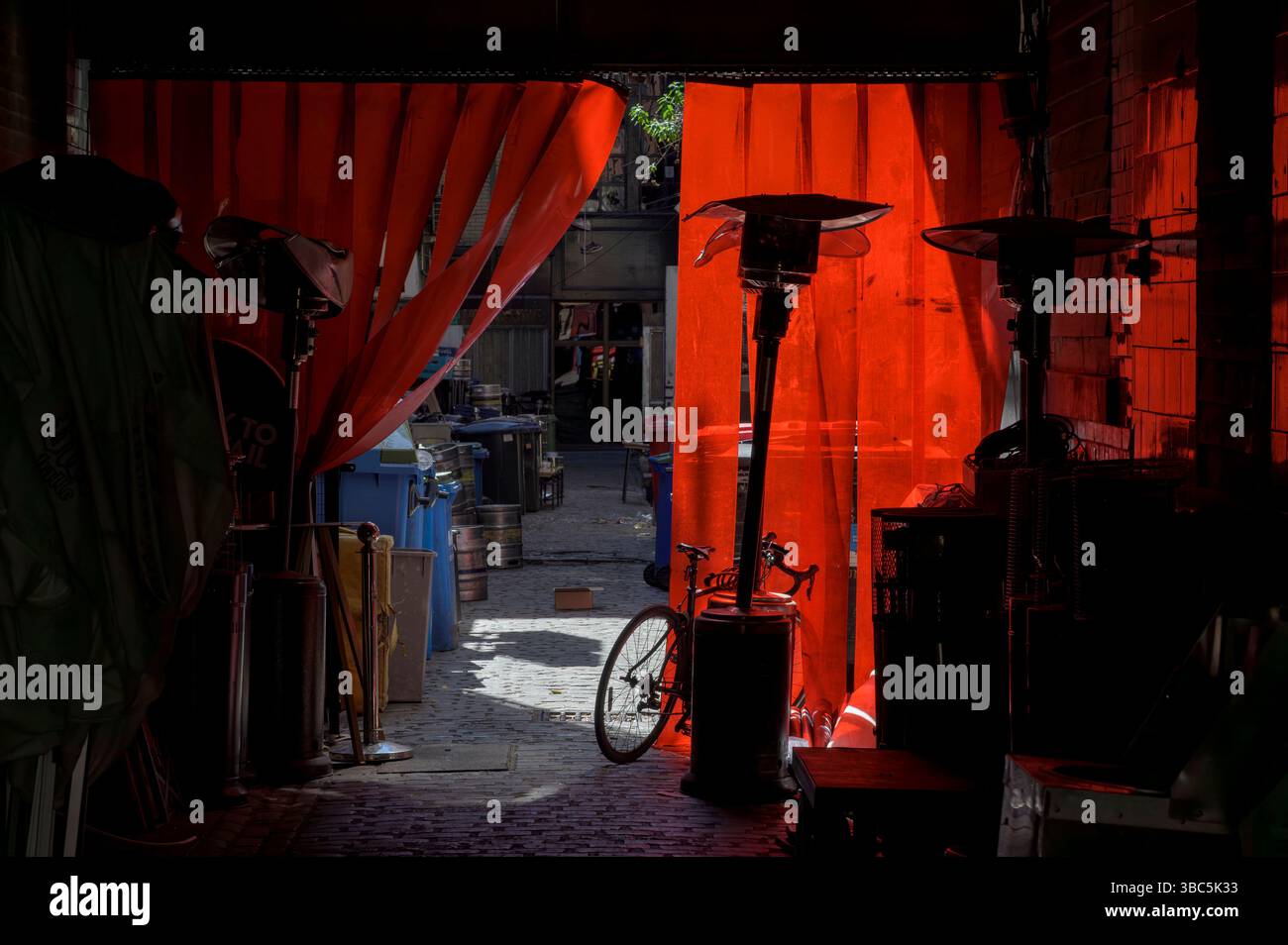 Luce solare che cade su tende di plastica rosse in una corsia di servizio aziendale, Regno Unito Foto Stock