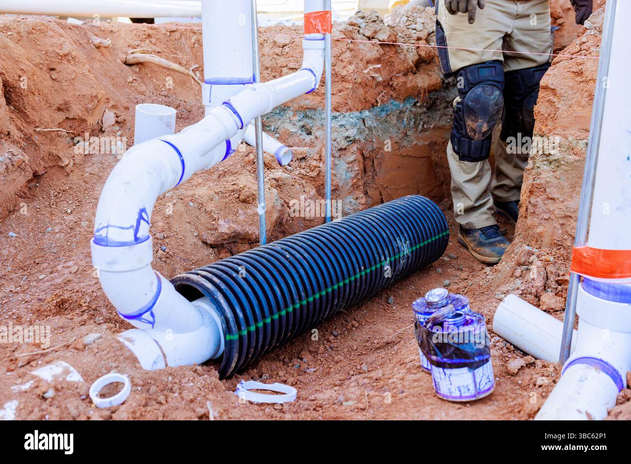 I lavoratori installano un sistema di drenaggio delle acque reflue in trincee e nella costruzione di materiali idraulici durante l'avanzamento dell'installazione Foto Stock