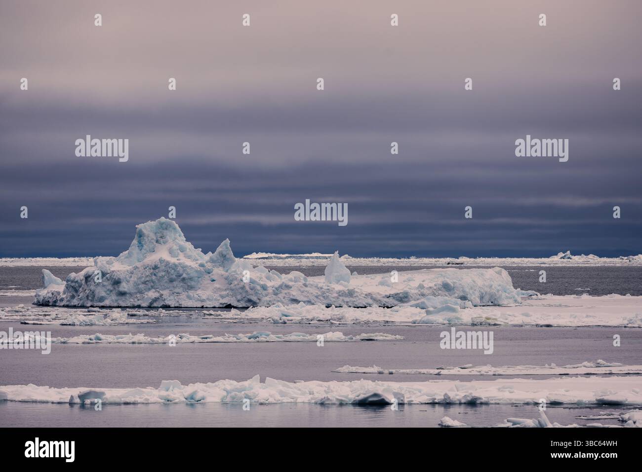 I banchi di ghiaccio si spostano sotto un cielo artico nuvoloso a Baffin Bay, Groenlandia occidentale. Una scena polare tranquilla e remota che mostra ghiaccio marino stratificato. Foto Stock