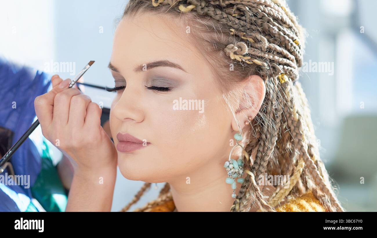 modello caucasico ciglia false durante la sessione di trucco.. Il modello ha una carnagione bianca e pulita Foto Stock