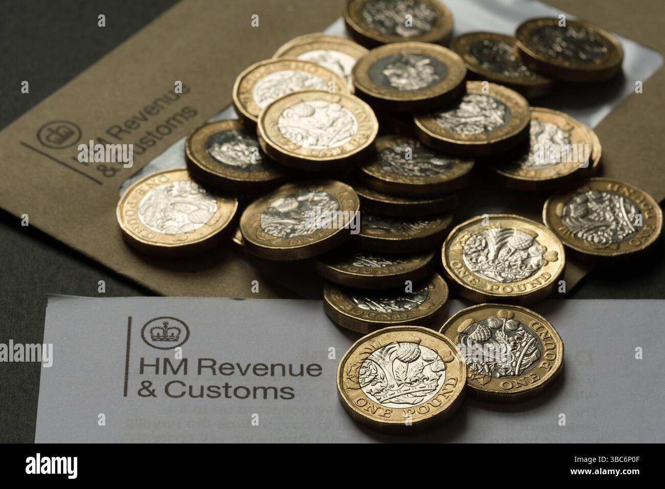 Monete britanniche da una sterlina sparse sulla corrispondenza HM Revenue & Customs, che rappresentavano imposte, risparmi e obblighi finanziari del Regno Unito, Stafford, ONU Foto Stock