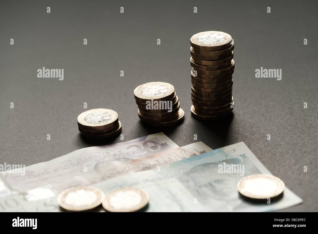 Le monete da una sterlina britannica in ordine ascendente collocate sopra le banconote da 5, 10 e 20, rappresentando la crescita finanziaria e il risparmio, Stafford, Unite Foto Stock