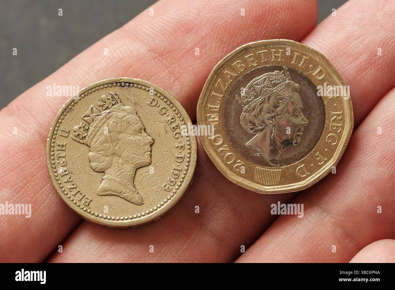 Vista ravvicinata del ritratto della regina Elisabetta II sulle vecchie e nuove monete inglesi da una sterlina tenute in mano, che illustrano i cambiamenti nella monetazione e nell'effigie reale, St Foto Stock
