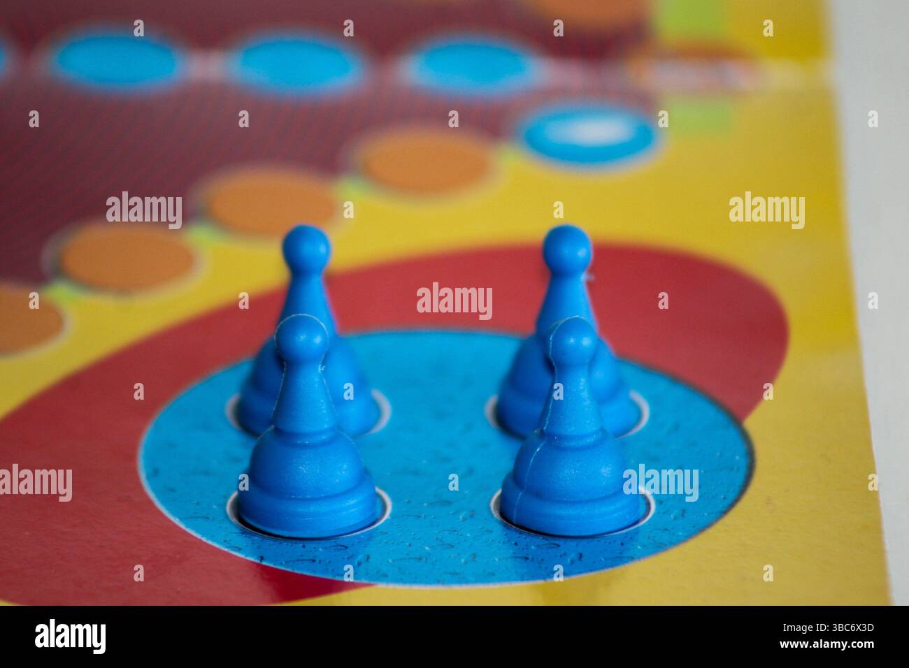 Primo piano di pedine blu nella zona di partenza del classico gioco da tavolo "Ludo". Gioco da tavolo, strategia e divertimento per tutta la famiglia. Foto Stock