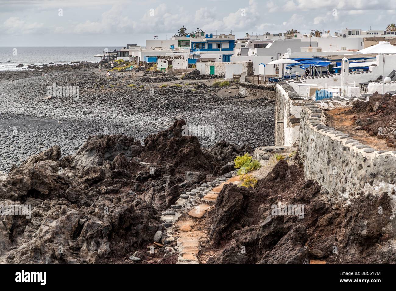 Edifici e pedoni costeggiano la riva di El Golfo a Lanzarote. Avenida Marítima, El Golfo, Lanzarote, Canarie, Spagna. Foto Stock