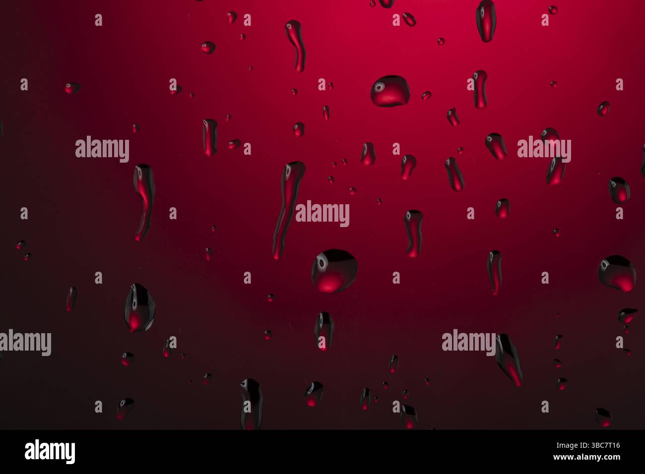 Gocce d'acqua su vetro su sfondo rosso Foto Stock