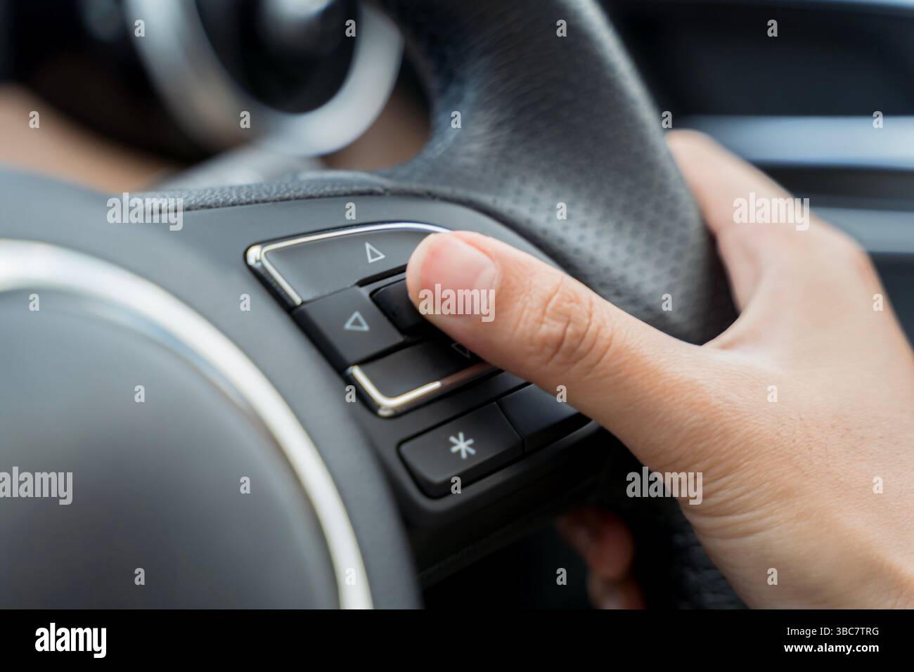 Il pulsante a mano del conducente sul volante di un'auto moderna, utilizzato per controllare le funzioni del veicolo come l'audio o il controllo della velocità di crociera. Concetto di Smart d Foto Stock