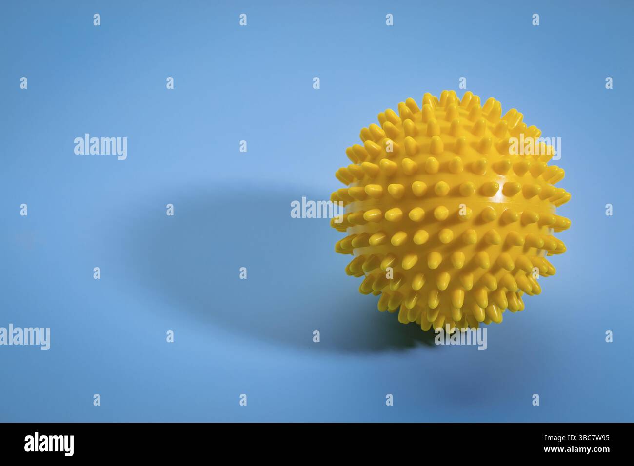 Rullo a sfera in gomma per auto-massaggio, riflessologia e rilascio miofasciale, sfondo blu con ombra Foto Stock