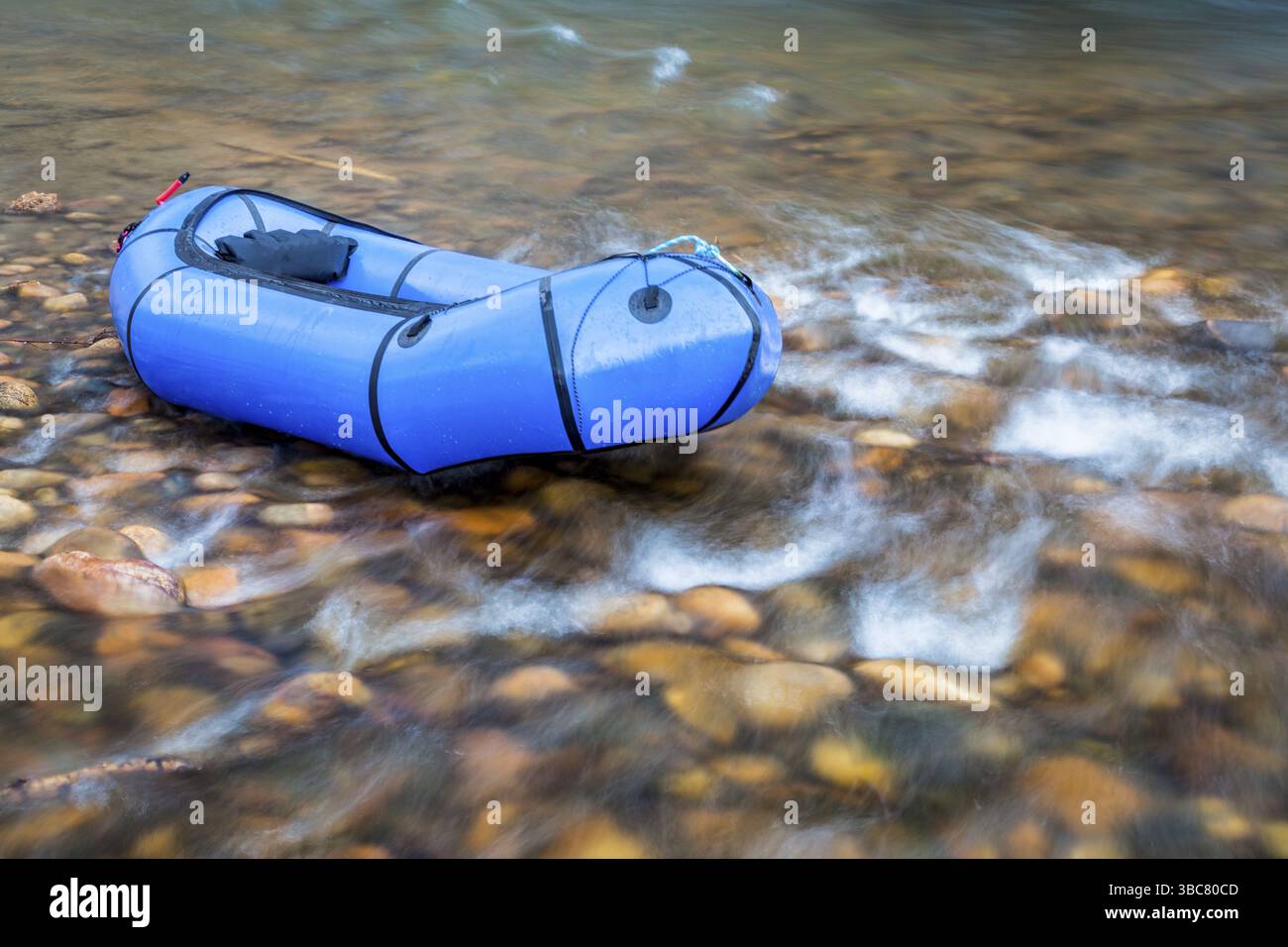 Un pacraft blu (zattera leggera per una persona utilizzata per le spedizioni o le corse avventurose) su un fiume poco profondo e roccioso Foto Stock