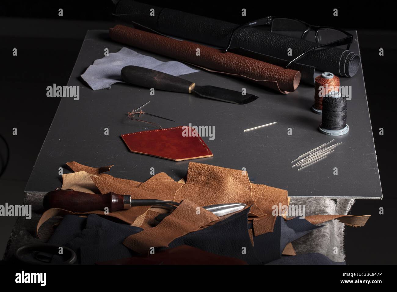 Tavolo da lavoro con gli strumenti di un artigiano per la produzione di pelletteria Foto Stock