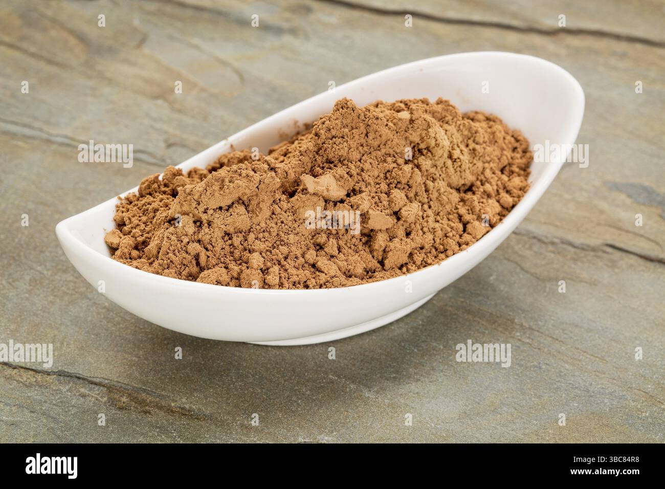 Una piccola ciotola in ceramica di polvere di cacao organico grezza ricca di antiossidanti e magnesio Foto Stock