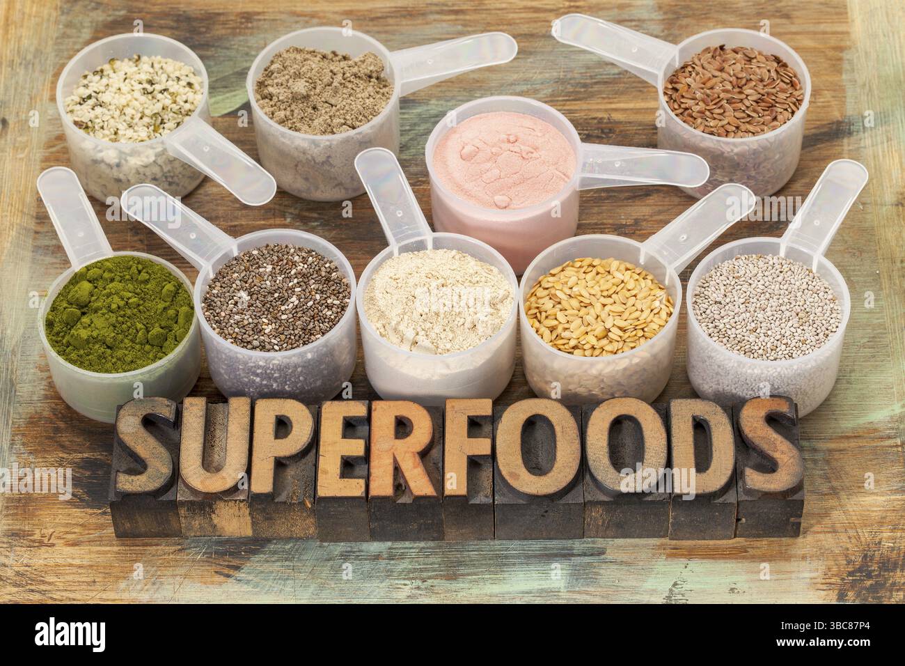 Superfood parola in tipografia tipo legno con sessole di plastica di semi e polveri sani (chia, lino, canapa, melagrana, polvere di frutta, girarrosto, mac Foto Stock