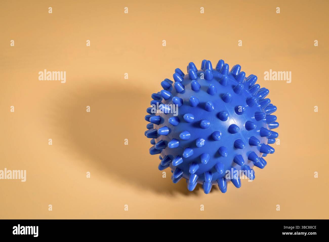 Rullo a sfera in gomma per auto-massaggio, riflessologia e rilascio miofasciale, sfondo beige con ombra Foto Stock