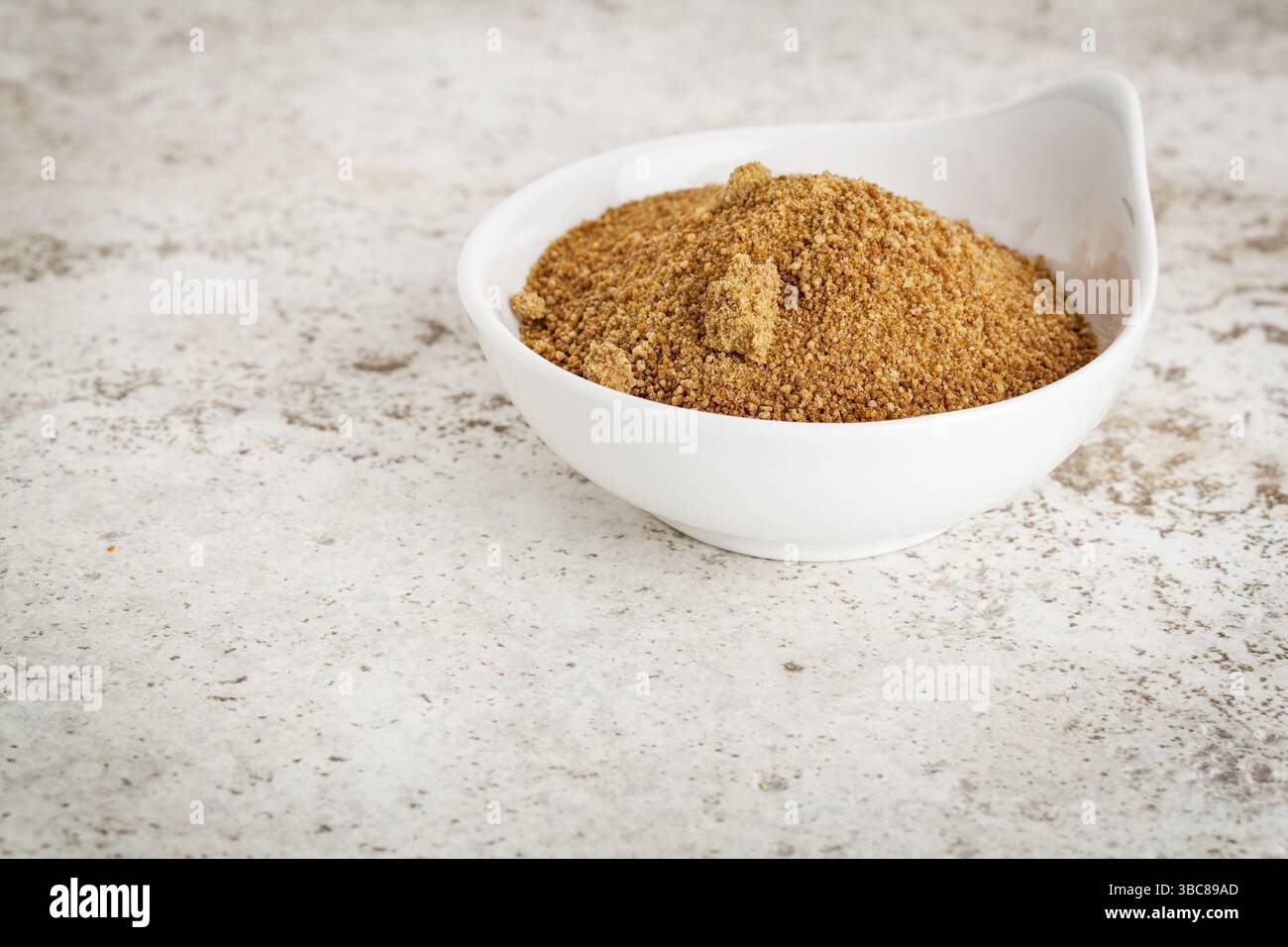 Piccola ciotola in ceramica con zucchero di palma da cocco non raffinato su uno sfondo piastrellato in ceramica con uno spazio di copia Foto Stock