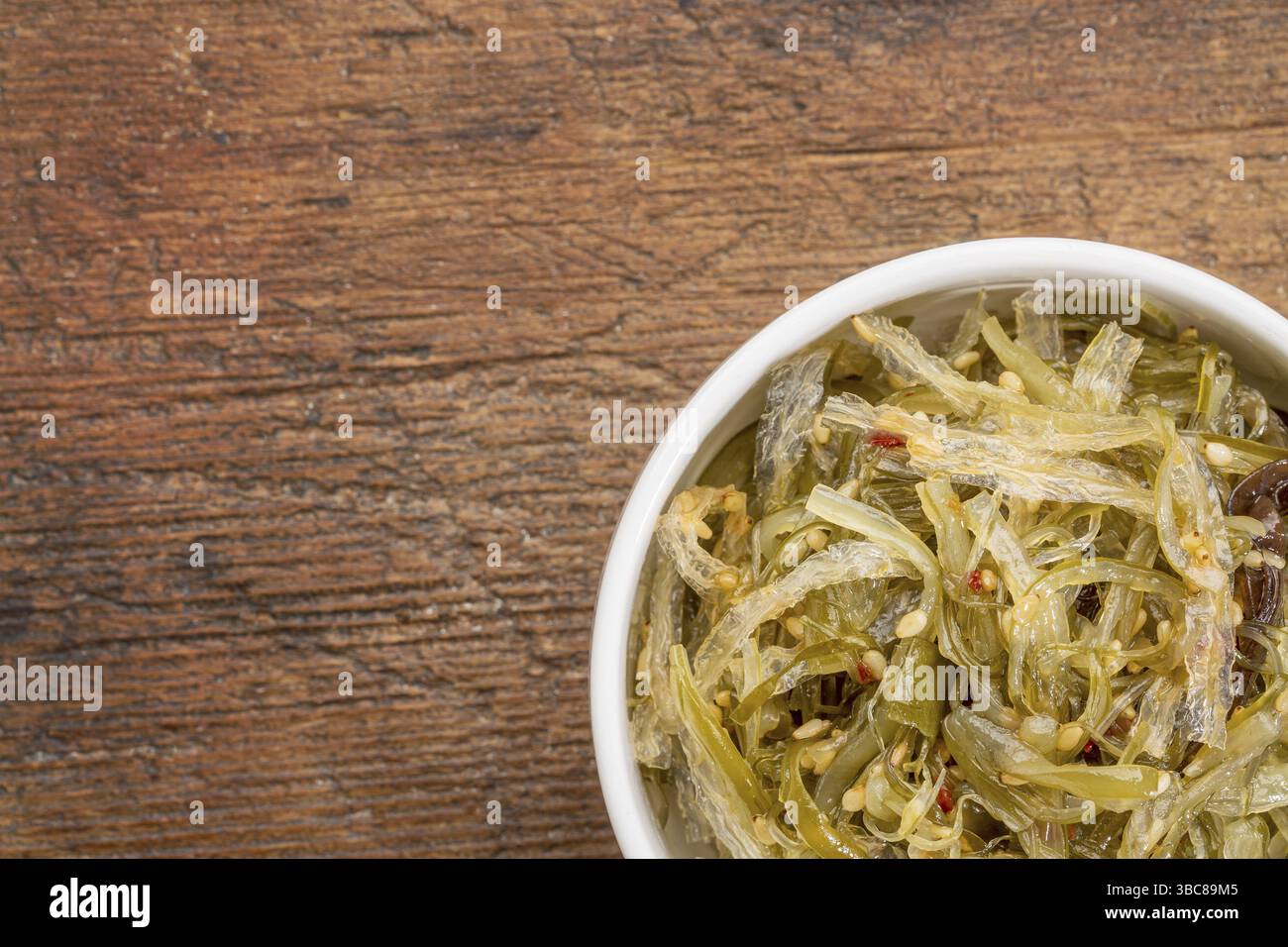 Una piccola ciotola in ceramica di insalata di alghe a base di agar-agar contro legno rustico Foto Stock