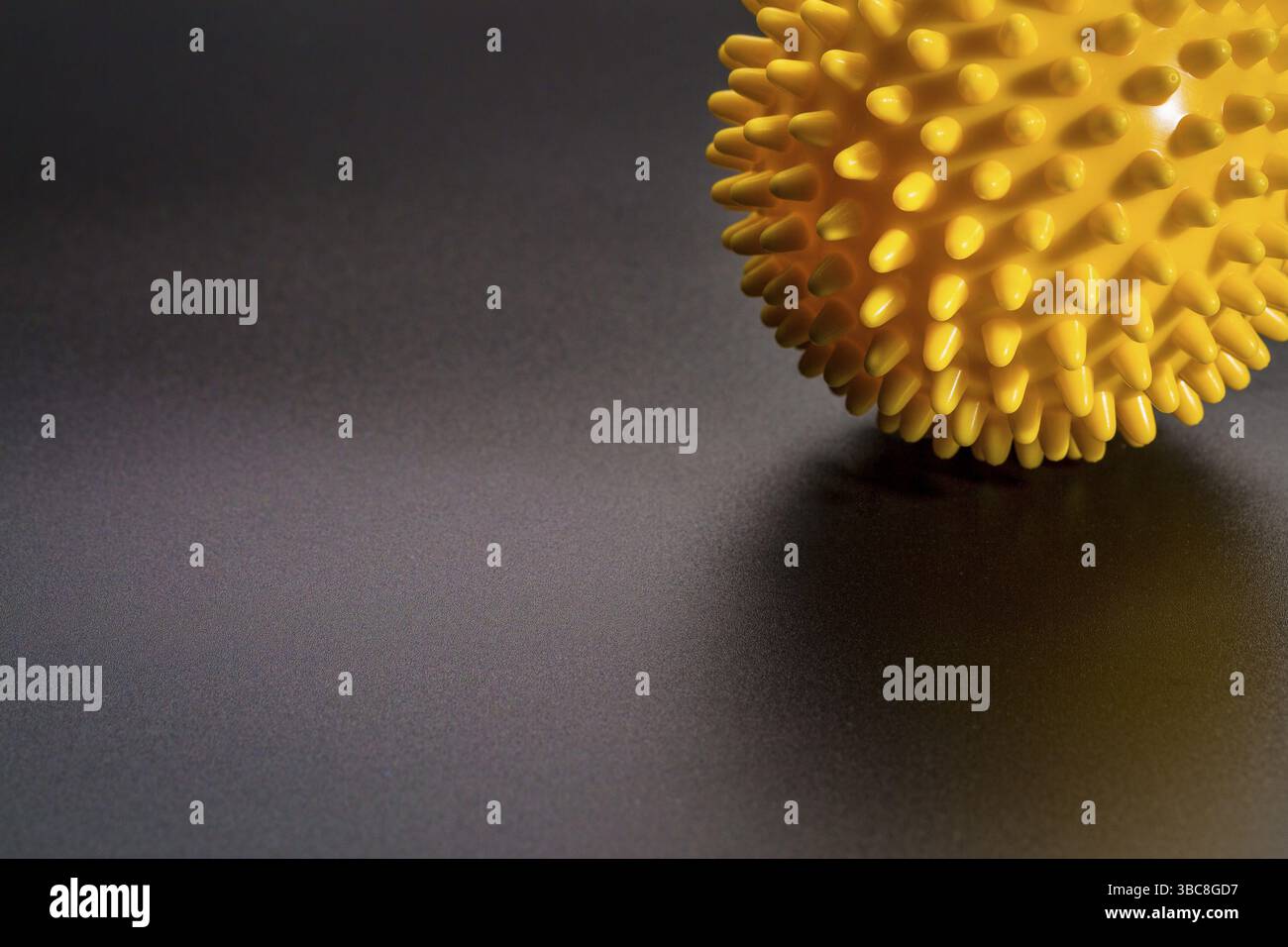 Rullo a sfera in gomma per auto-massaggio, riflessologia e rilascio miofasciale, sfondo nero con spazio di copia Foto Stock