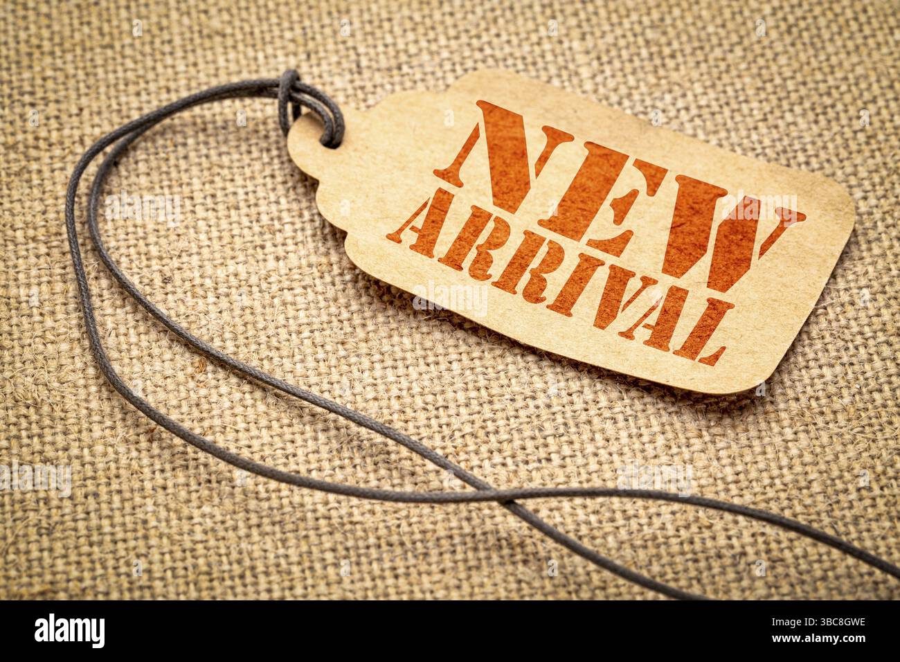 Nuovo cartello di arrivo - un cartellino del prezzo della carta con spago su tela a strascico Foto Stock