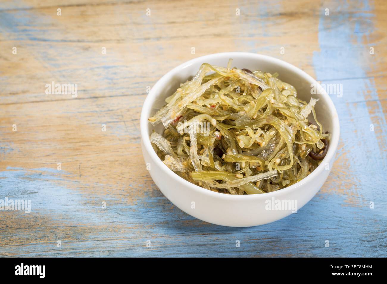 Una piccola ciotola in ceramica di insalata di alghe a base di agar-agar contro il legno grunge Foto Stock