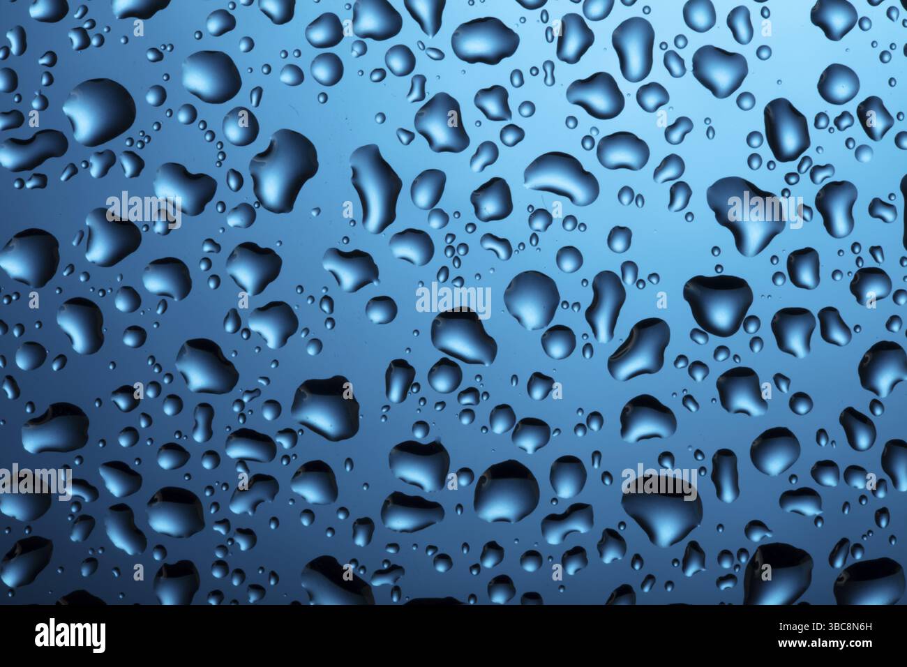 Gocce d'acqua su vetro su sfondo blu Foto Stock