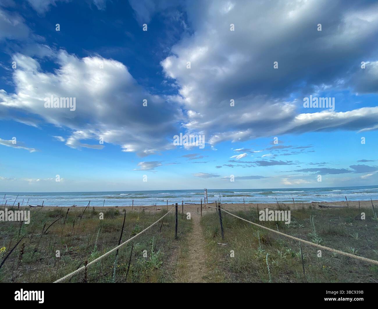 Recinzione di corda che guida verso la spiaggia sabbiosa di Pineto, sotto un cielo nuvoloso in Abruzzo, Italia Foto Stock